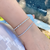 Bracelete folheado a ródio branco com bolinhas e zircônias, adornando um pulso feminino.
