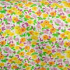 Tela batista estampada con flores amarillas, lilas y detalles verdes sobre fondo blanco