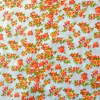 Tela de microfibra estampada con flores naranjas y rojas sobre fondo blanco