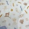 Gabardina estampada con motivos marinos, incluyendo peces, pulpos y corales en tonos suaves.