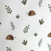Tela de gabardina estampada con tortugas y hojas verdes sobre fondo blanco.