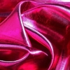 Tela de lame fucsia con brillo, mostrando pliegues y texturas.