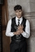 Man wearing a six-button black leather tailored vest from the luxury brand FRANCUIR, with a white shirt and leather tie also from the FRANCUIR leather boutique, posing in an elegant setting.