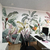Mural botánico con hojas y flores en tonos verdes y rosados, decorando una oficina moderna.