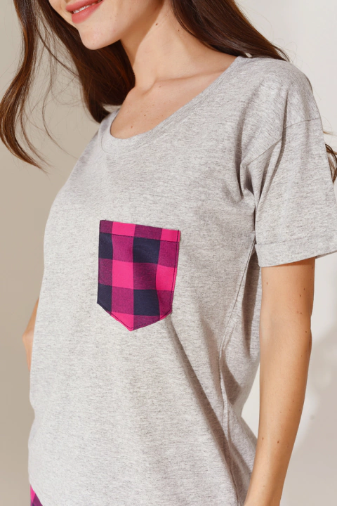 Mujer usando una remera gris con un bolsillo de cuadros en tonos rosa y negro, y remera gris.