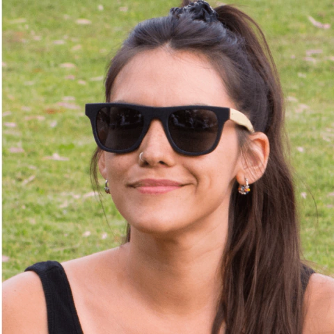 Mujer con anteojos de madera (patillas) y acetato (frente) color negro de forma rectangular con lentes de sol polarizados modelo Mykonos marca Nómade