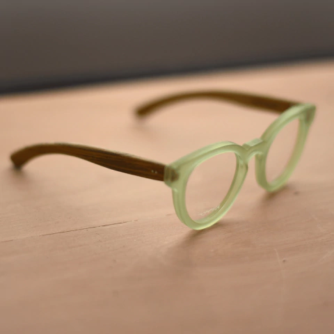anteojos de forma redondeada con puente tipo llave para colocar lentes de aumento hechos en acetato color verde brillante traslucido (frente) y madera (patillas) modelo Chalten marca Nomade vista lado derecho