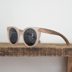 anteojos de madera (patillas) y acetato (frente) color rosa traslucido de forma redondeada con lentes polarizados modelo Vera marca Nómade (vista izquierda)