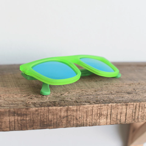anteojos de sol de acetato coloverde brillante mate con lentes espejados polarizados color azul modelo Tulum PA marca Nómade sobre fondo de madera