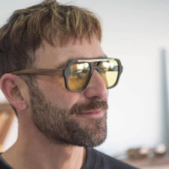 hombre con anteojos de madera (patillas), acetato (frente) color negro y aplique de acero inoxidable con lentes tintados color amarillo perfil | Nomade