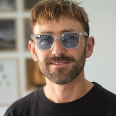 hombre con anteojos de madera (patillas) y acetato color cristal (frente) con lentes azules modelo Munich marca Nómade