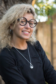 Mujer con anteojos de madera (patillas) y acetato (frente) color negro de forma redondeada para colocar lentes de aumento modelo Viena marca Nómade
