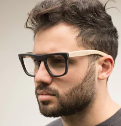 hombre con anteojos de madera (patillas) y acetato color negro mate (frente) para colocar lentes de aumento de forma rectangular modelo Tulum marca Nómade vista perfil