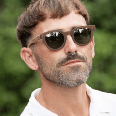 Hombre usando anteojos de sol de madera y acetato Chalten, con fondo natural desenfocado.