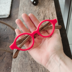Anteojos de madera y acetato Liverpool en una mano, con armazón naranja y patillas de madera, sobre un fondo de madera.