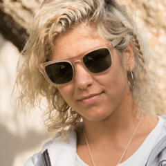 mujer con anteojos de sol de madera (patillas) y acetato (frente) color rosa traslucido terminación mate de forma rectangular modelo Tulum marca Nómade vista frente