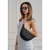 Cartera de hombro Afrodita en color negro, modelo utilizado por una mujer que viste un vestido gris y gafas de sol.