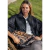 Mujer sentada al aire libre con capa negra y riñonera animal print con etiqueta Neo Bag