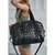 Bolso Cruz negro deportivo de material brillante, con asas y correa ajustable, sostenido por una mujer con top verde.