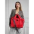 Tote bag roja con diseño acolchado, sostenida por una mujer que viste un blazer gris.
