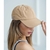 Gorra deportiva color beige en la cabeza de una mujer, con un fondo claro.