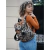 Mochila Hali simil neoprene con diseño de leopardo, llevada por una mujer con una blusa de manga larga naranja y jeans, posando en un entorno urbano.