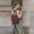 Mochila Luna Bomber de color marrón con dos bolsillos frontales y detalles en metal llevada por una modelo mujer