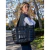 Cartera Melisa negra de estilo shopper, con textura acolchada, llevada por una mujer en un entorno natural.
