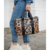 Cartera tote de estampado animal print, sostenida por una mujer que viste jeans y zapatillas deportivas.