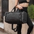 Bolso Positano negro con diseño acolchado, llevado por una mujer en ropa deportiva.