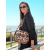 Una mujer sonriente lleva una bandolera de neoprenw con estampado de leopardo en un entorno exterior soleado.