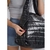 Bolso shopper negro con textura acolchada, siendo abierto por una mujer que viste una camiseta gris y un short de mezclilla.