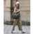 Mujer caminando por la calle con un bolso Taormina de color verde, usando un conjunto de ropa de tono claro y una gorra.