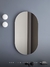 Espelho moderno abstrato oval sem moldura em um banheiro com parede cinza Lustres Gênesis Site online venda de Lustres e Iluminação