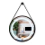Espelho Touch Screen Redondo com LED Luz Direta pendurado em uma parede, refletindo uma sala de estar decorada com plantas e móveis modernos. Lustres Genesis loja online de Lustres e Iluminação Decorativa