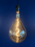Lâmpada de Filamento de Led Supersize A160 4W Soft da GMH acesa em fundo azul Lustres Gênesis loja online de Lustres e Iluminação Decorativa