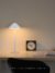 Luminária de Mesa Abajur de LED Sem Fio Lunaris Preto em uma mesa de escritório ao lado de um relógio e livro aberto. Venda de lustres é na Lustres Gênesis