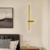 Arandela Moderna Fit Linear Slim de LED Dourada instalada em um quarto ao lado de uma cabeceira de cama.