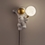 Arandela moderna em formato de astronauta segurando uma lâmpada em forma de lua, ideal para decoração de quarto infantil, cabeceira de cama e lavabo. Lustres Genesis loja online de Lustres e Iluminação Decorativa