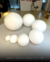 Vários globos de vidro fosco leitoso em diferentes tamanhos dispostos em um ambiente interno. Lustres Gênesis loja online de Lustres e Iluminação Decorativa