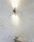 Arandela Moderna Rudá Café Fosco instalada em parede de mármore branco, iluminando o ambiente com luz suave. Arandela Moderno Botton de LED Dourada da SkyLight, modelo SKY-3111AR-DO, com design circular e detalhes texturizados. Lustres Gênesis Site online