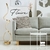 Luminária de coluna moderna Fluire em uma sala de estar com sofá cinza, mesa de centro branca e decoração minimalista. Lustres Gênesis Site online venda de Lustres e Iluminação decorativa