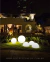 Luminária de Chão Meia Esfera Soleil Branca iluminando jardim à noite. Lustres Gênesis loja online de Lustres e Iluminação Decorativa