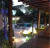 Luminária de Chão Meia Esfera Soleil Branca iluminando área externa com piscina e jardim à noite. Lustres Gênesis loja online de Lustres e Iluminação Decorativa