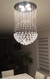 Lustre de cristal em formato de bola pendurado no teto de uma sala de jantar. Lustres Gênesis loja online de Lustres e Iluminação Decorativa