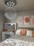 Lustre de cristal em formato de bola no teto de um quarto decorado com cama e espelho. Lustres Gênesis loja online de Lustres e Iluminação Decorativa