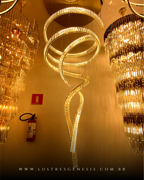 Lustre pendente de cristal em formato espiral, ideal para casas com pé direito duplo e alto, da marca Sindora. Lustre Grande Arandela Moderno Botton de LED Dourada da SkyLight, modelo SKY-3111AR-DO, com design circular e detalhes texturizados. Lustres Gên