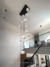 Lustre pendente Cosmos Jabuticaba com 21 globos leitosos brancos em ambiente de pé direito duplo alto e escadas de casas modernas teto alto, escada preta e cortina grande. Lustres Gênesis