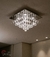 Lustre de cristal em formato de pirâmide instalado no teto de uma sala, destacando-se pela elegância e sofisticação. Lustres Gênesis loja online de Lustres e Iluminação Decorativa