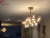 Lustre pendente dourado fosco com design moderno e lâmpadas âmbar iluminando uma sala de jantar elegante. Lustres Gênesis loja online de Lustres e Iluminação Decorativa
